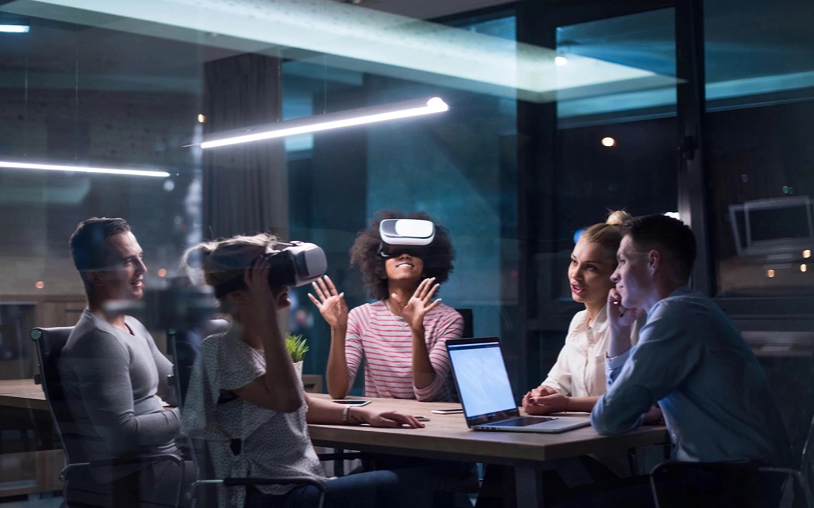 Grupo de personas trabajando en una oficina usando realidad virtual y laptops conectadas a una red wifi rápida y estable.